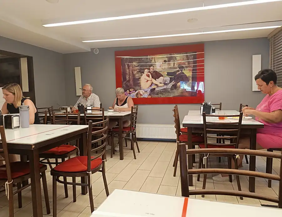 Sala z białymi stołami i czerwonymi krzesłami